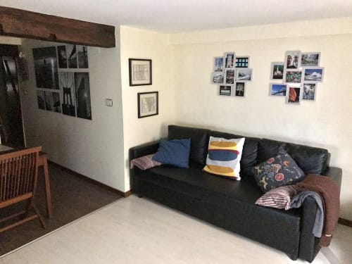 Living room of 2-bedroom apartment in Lekeitio with black sofa, colorful pillows, framed photos, and wooden furniture