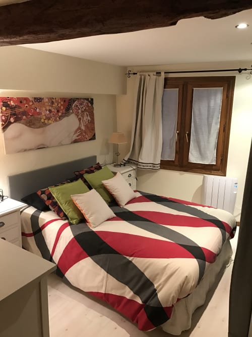 Bedroom at Urrondo apartment in Lekeitio with striped red, black and white bedding, green pillows and wooden ceiling beams