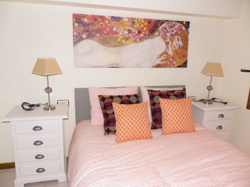 Bedroom at Urrondo apartment in Lekeitio with pink bedding, orange pillows, nightstands with lamps, and abstract artwork