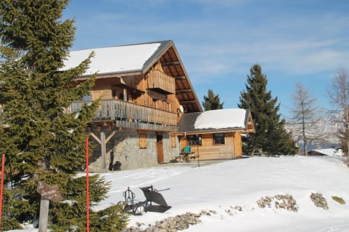 Le refuge alpin Chalet La Louvière à Fontcouverte-La Toussuire enneigé, avec son architecture en bois et ses sapins