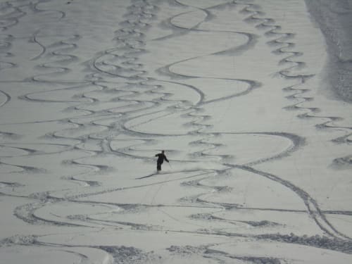 Skiër die door de sneeuwhellingen van La Toussuire afdaalt, nabij Chalet La Louvière in de Franse Alpen