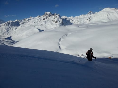Skiër die een besneeuwde alpiene helling afdaalt bij Chalet La Louvière in Fontcouverte-La Toussuire, Franse Alpen