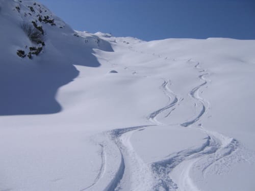 Skisporen kronkelen over de besneeuwde helling van La Toussuire bij Chalet La Louvière, Franse Alpen
