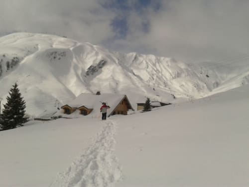Sneeuwbedekte berghutten met houten chalets in Fontcouverte La Toussuire, wandelaar in alpien winterlandschap