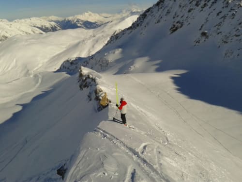 Skieër stijgt op besneeuwde alpiene helling met bergpieken bij La Toussuire, Fontcouverte
