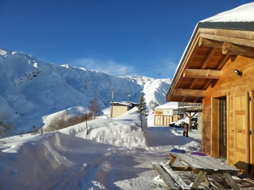 Chalet en bois dans un village alpin enneigé avec pics couverts de neige à La Toussuire