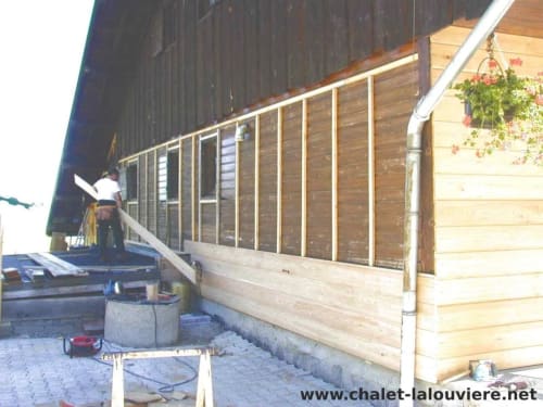 Chalet La Louvière met houten terras, eetgedeelte en hangende bloemen in Fontcouverte-La Toussuire