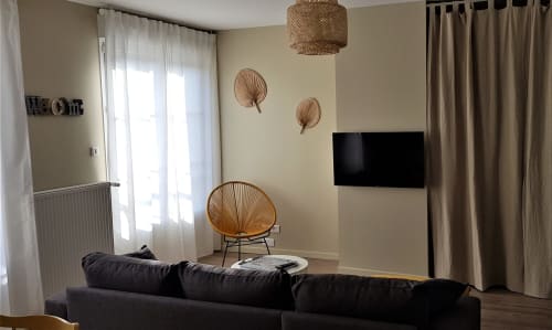 Espace de détente moderne dans l'appartement La Java Bleue de la Maison Virginie B&B, Montargis, avec canapé noir, fauteuil tressé et