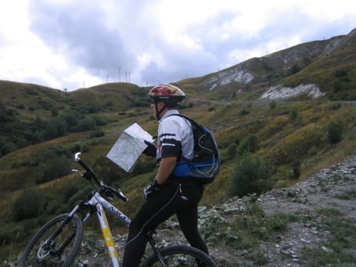 Mountainbiker raadpleegt kaart in glooiende Alpische heuvels nabij Fontcouverte, La Toussuire, ideaal voor buitenactiviteiten bij Chalet