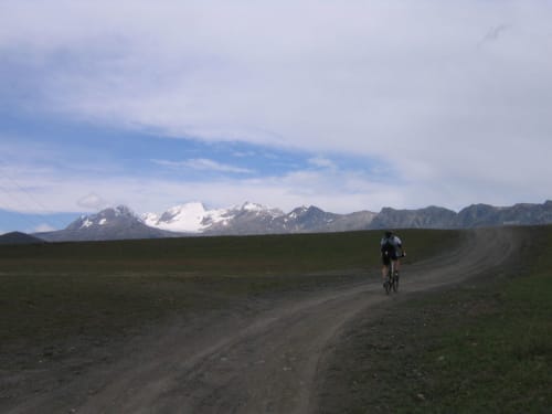 Fietser op bergpad met sneeuwtoppen van de Alpen, Fontcouverte-La Toussuire