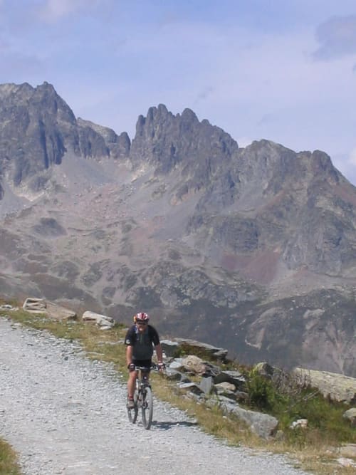 Fietser op bergweg met dramatische rotspieken in de buurt van La Toussuire, Chalet La Louvière