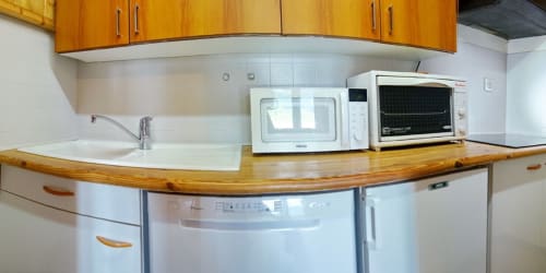 Kitchen with wooden countertop, white appliances, and microwave at Chalet La Louvière, Fontcouverte