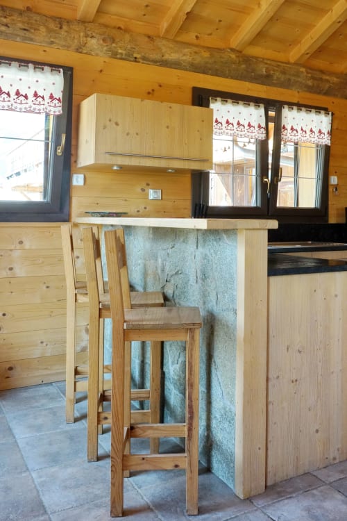 Rustic wooden kitchen and dining area at Chalet La Louvière in La Toussuire with bar seating and alpine decor