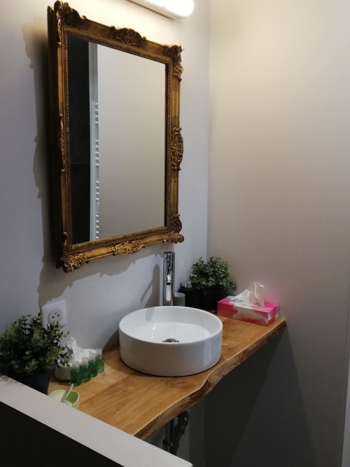 Élégante vasque blanche ronde et miroir doré au-dessus du meuble en bois de la salle de bains de La Tour Grégoire à Clermont-Ferrand