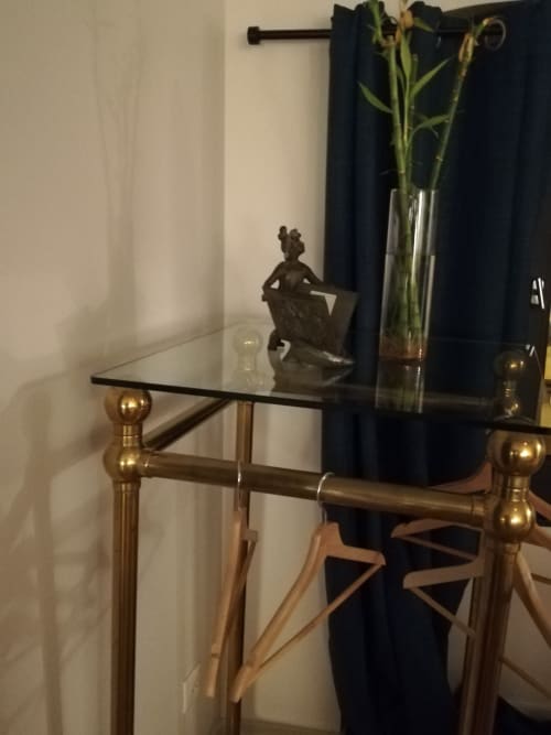 Bureau élégant en verre aux pieds en laiton dans la Chambre Pavin de La Tour Grégoire, agrémenté d'une statue en bronze et de fleurs fraîches