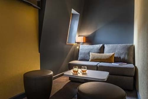 Modern lounge area at Hotel Residence Europe & Spa in Clichy with gray sofa, cocktails, and ambient lighting