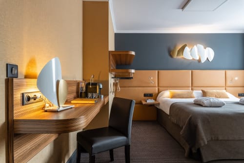 Modern junior suite at Hotel Residence Europe & Spa in Clichy with wooden desk, blue headboard, and contemporary lighting
