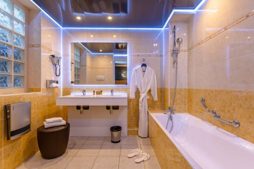 Modern bathroom in Junior Suite at Hotel Residence Europe & Spa, Clichy, featuring double sink, bathtub, and blue neon