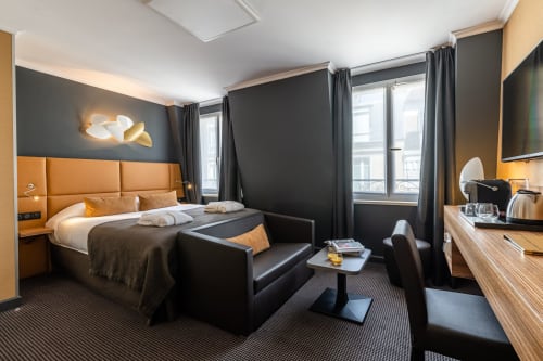 Executive Room at Hotel Residence Europe & Spa in Clichy featuring orange headboard, dark walls, and modern seating area