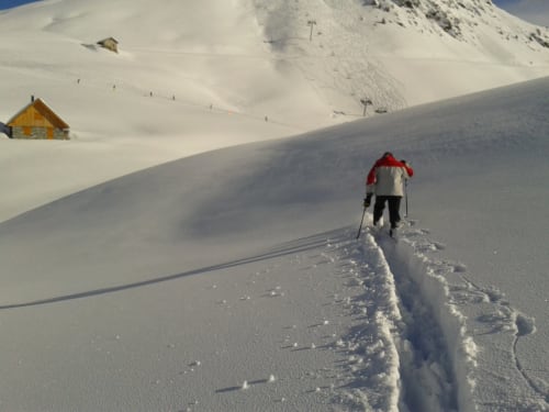 Skiër die een besneeuwde bergafhelling oploopt bij Chalet La Louvière in Fontcouverte-La Toussuire, Franse Alpen