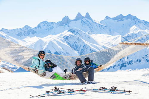 Familie geniet in een nethangstoelmat met ski's in de sneeuwrijke Alpen bij Fontcouverte-La Toussuire