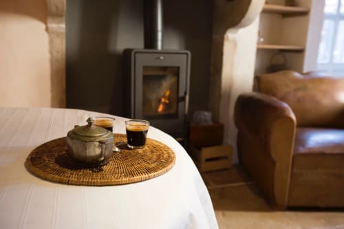 Cozy living room at Clos Saint Jacques B&B in Meursault with tea service, wood stove, and leather seating