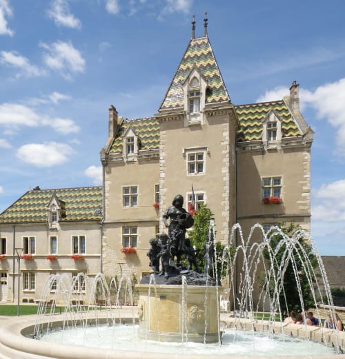 Schloss Clos Saint Jacques mit charakteristischen grünen Ziegeldächern und Brunnen in Meursault, Frankreich