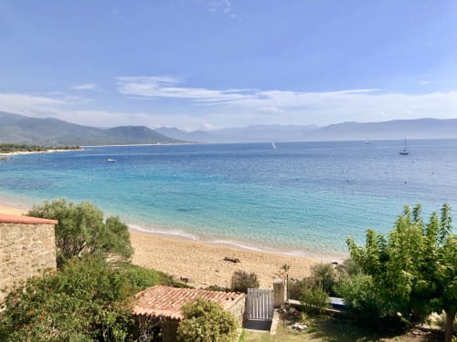 Plage méditerranéenne turquoise aux Villas Marincelu avec voiliers, montagnes et village côtier à Porto Pollo, Corse