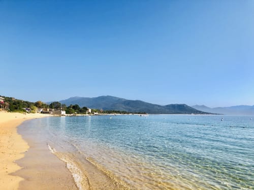 Playa de arena blanca con aguas turquesas cristalinas y montañas en Villas Marincelu, Porto Pollo, Córcega