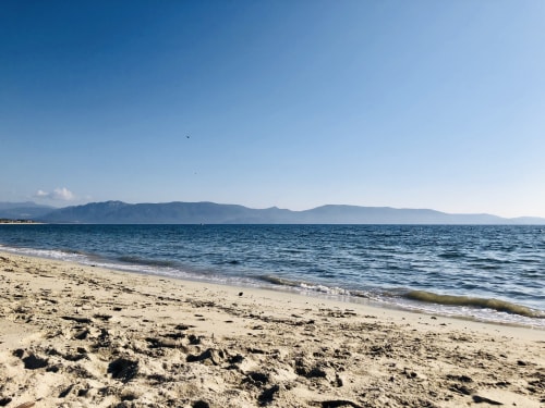 Plage de sable fin aux Villas Marincelu à Porto Pollo, Corse, avec mer turquoise et montagnes