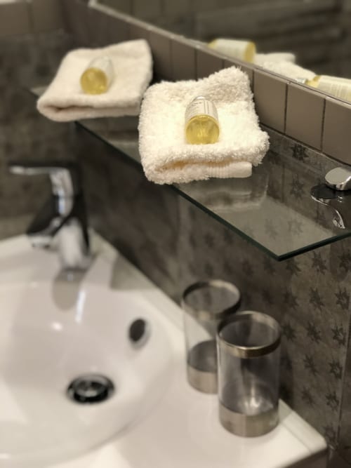 Luxury bathroom amenities at Villas Marincelu with folded white towels, yellow soap, and sink in Porto Pollo