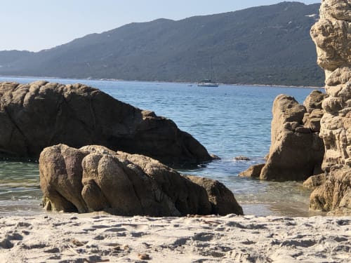 Plage rocheuse pittoresque aux Villas Marincelu à Porto Pollo avec voilier et montagnes boisées