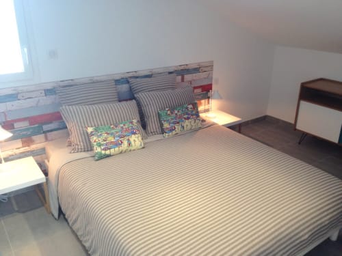 Chambre lumineuse de l'appartement Côte Et Dune avec literie rayée, coussins colorés et tête de lit rayée à Biscarrosse Plage