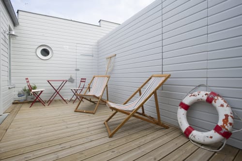 Gemütliche Terrasse eines Strandhauses mit gestreiften Liegestühlen, Holzmöbeln und Rettungsring bei Les Filles du Bord de Mer