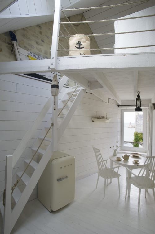 Helles Küstenhäuschen mit Hochbett, weißen Shiplap-Wänden, Vintage-Kühlschrank und Essbereich mit Meerblick