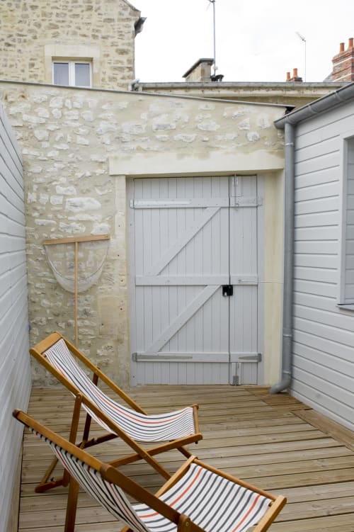 Privater Innenhof mit gestreiften Liegestühlen, Steinhaus und weißer Scheunentür in Les Filles du Bord de Mer, Port-en-Bessin