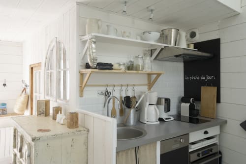 Moderne kleine Küche in der Ferienhütte La Cabane des Pêcheurs mit weißen Regalen, grauer Arbeitsplatte und Nautik-Dekor