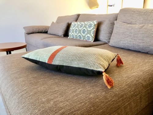 Casa Felice villa living room with grey sofa, decorative pillows, and patterned floor cushion with orange tassels at Villas