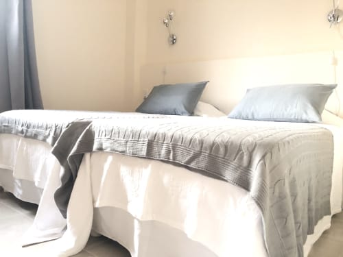 Twin beds with white linens and gray pillows in a bright bedroom at Villas Marincelu villa, Porto Pollo, Corsica