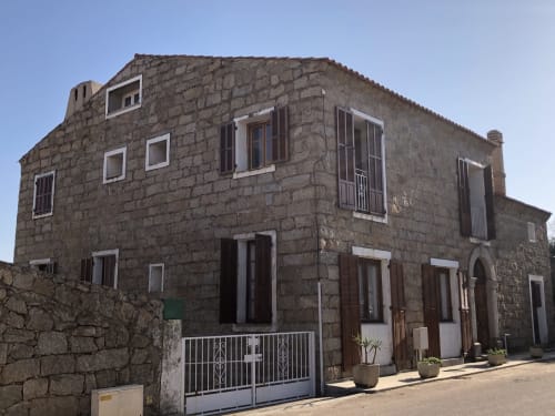 Villas Marincelu stone hotel building in Porto Pollo, Serra di Ferro with white-trimmed windows and wooden shutters