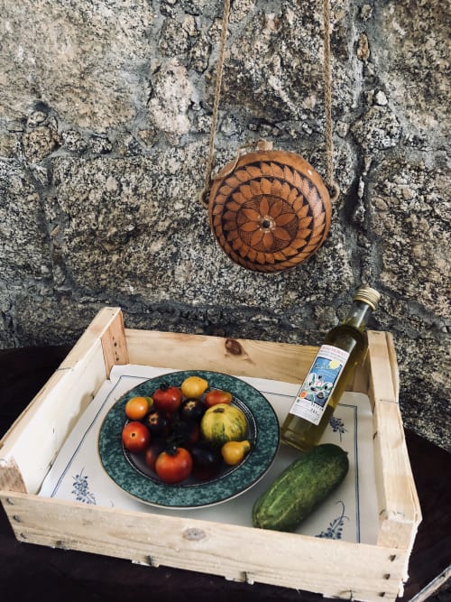 Plateau en bois avec produits frais et huile d'olive devant un mur de pierre rustique à Villas Marincelu, Corse
