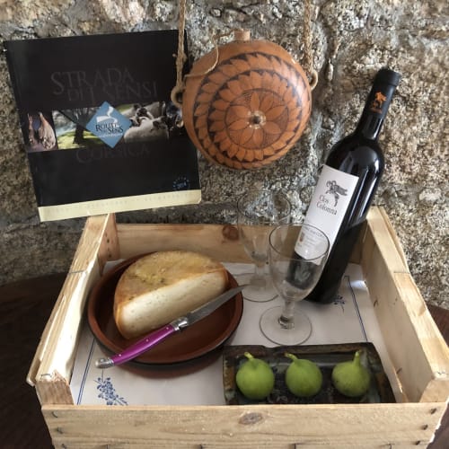 Plateau de bienvenue aux Villas Marincelu avec vin, pain, fromage, poires et décor corse traditionnel sur mur de pierre