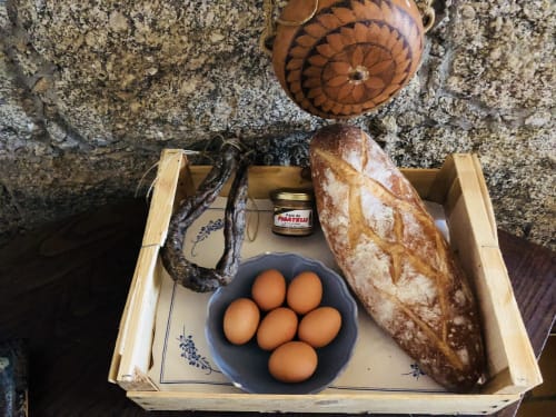 Plateau d'accueil rustique aux Villas Marincelu avec œufs frais, pain, saucisse et produits locaux à Serra di Ferro