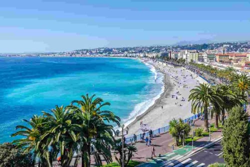 Plage méditerranéenne pittoresque aux eaux turquoise, palmiers et bâtiments de la côte d'azur
