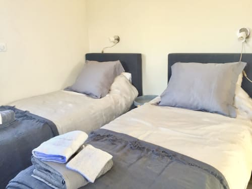Twin beds with gray headboards and blue pillows at Villas Marincelu villa, folded towels on bed