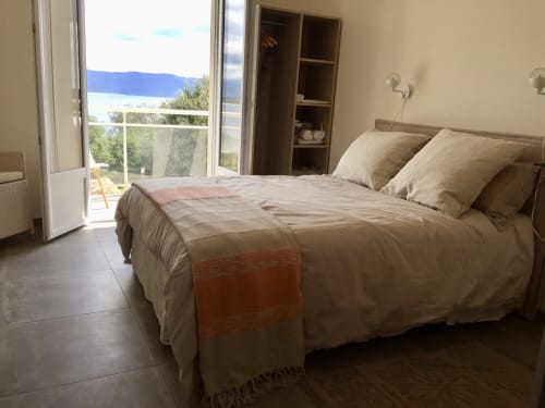 Spacious bedroom at Casa Serena villa with sea view balcony, beige bedding, and modern amenities overlooking Corsican