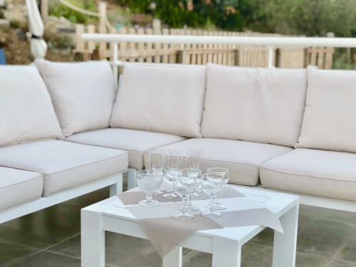 Elegant outdoor lounge at Casa Serena villa with cream sectional sofa, white coffee table, and glasses overlooking sea view