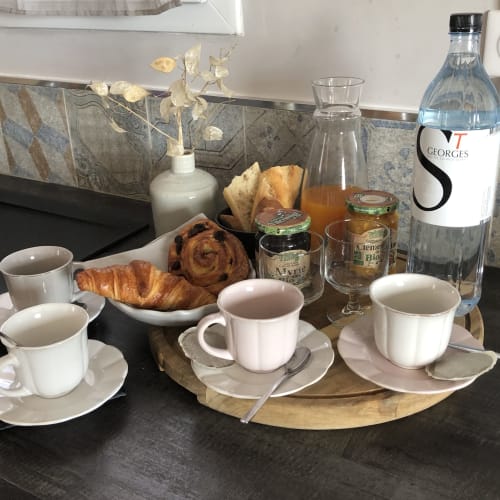 Table de petit-déjeuner aux Villas Marincelu avec pâtisseries, tasses de café, bouteille d'eau et fleurs séchées à Porto Pollo, Corse.