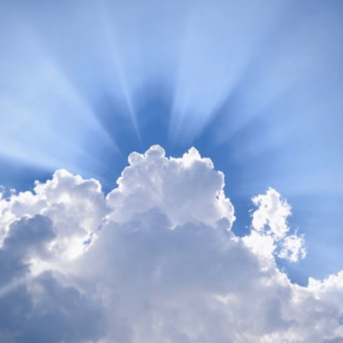 Bright sunrays breaking through white clouds in blue sky above Château d'Hassonville, Marche-en-Famenne