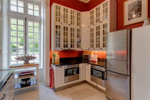 Modern kitchen with red walls, cream cabinetry, and stainless steel appliances at Château d'Alexis de Tocqueville,